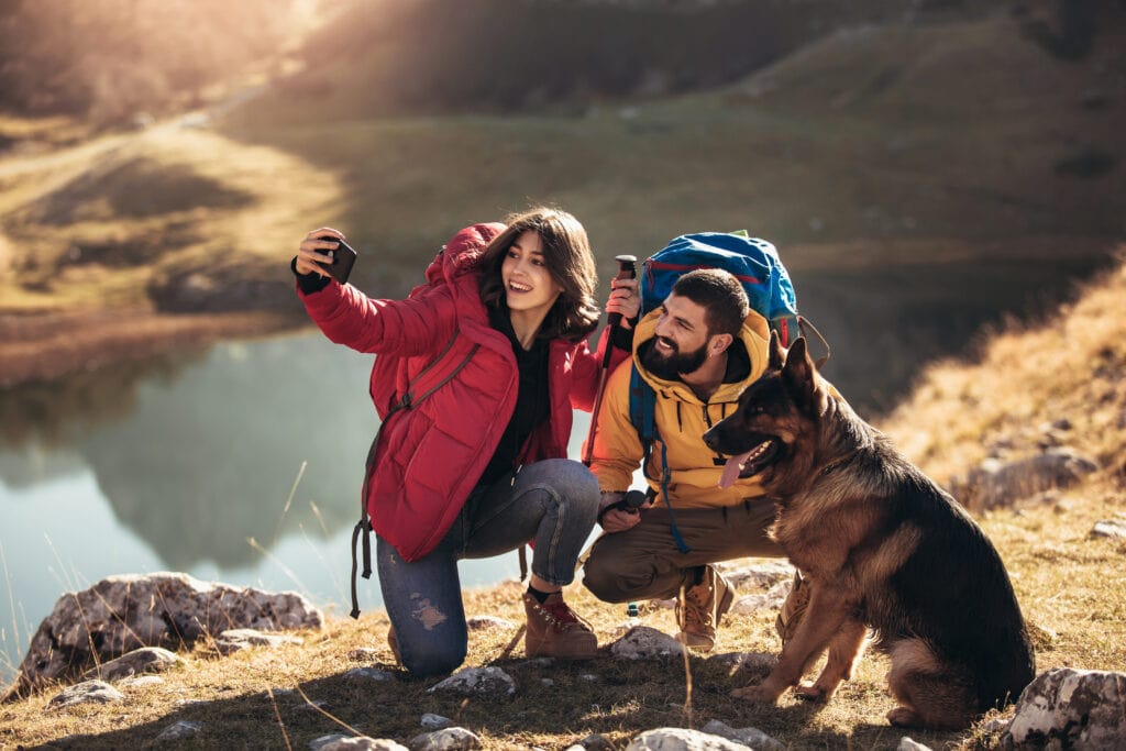 family enjoying hiking with their german shepherd, taking a selfie by the river